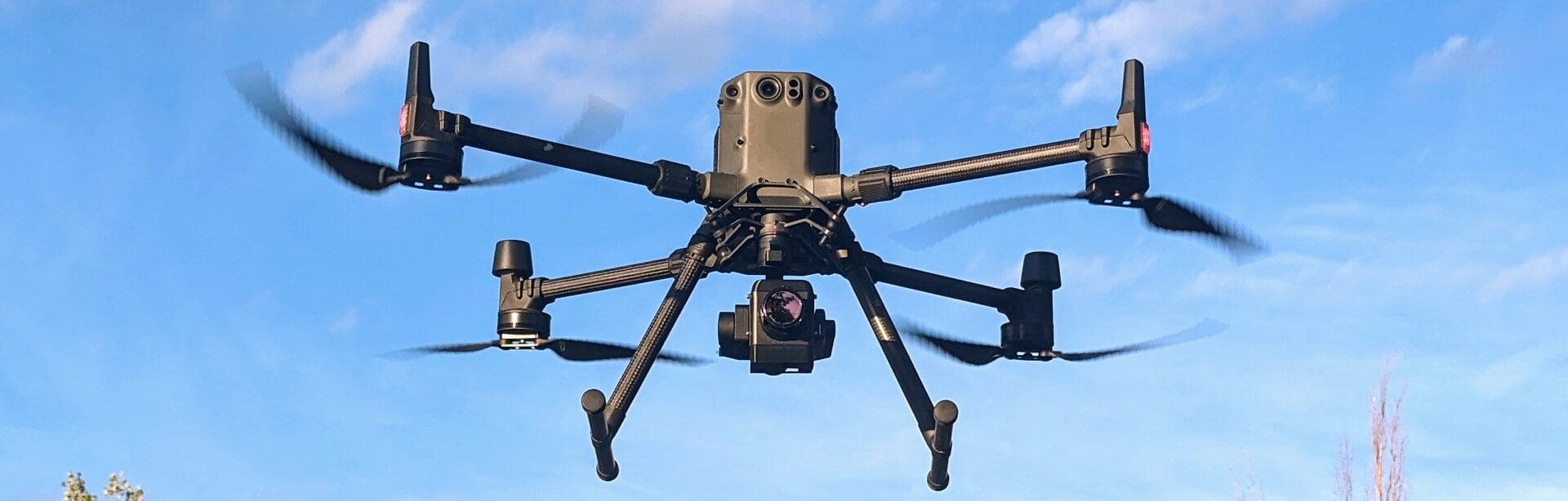 Close-up of a professional drone with a camera against a blue sky.
