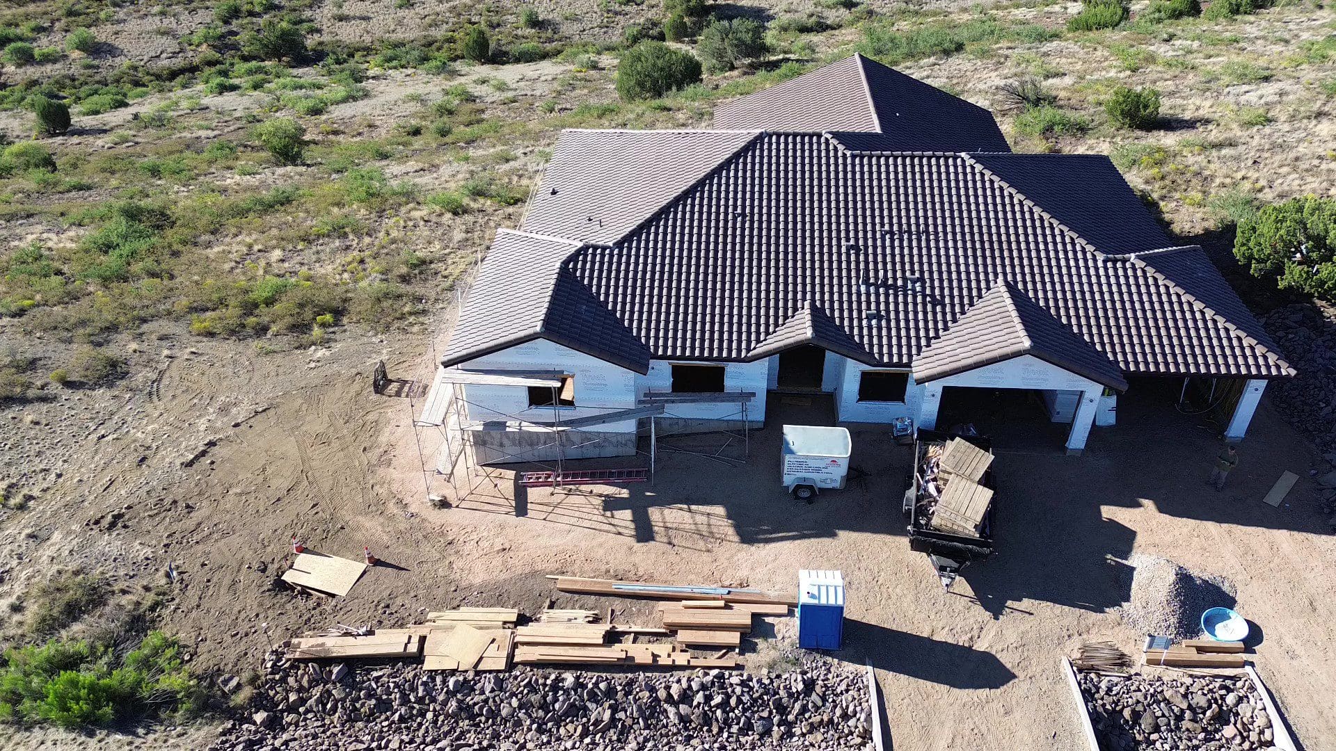 A house under construction with a dark tiled roof and unfinished exterior walls.