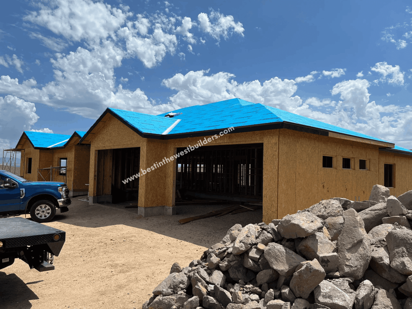 Newly constructed house with a blue roof under a cloudy sky.